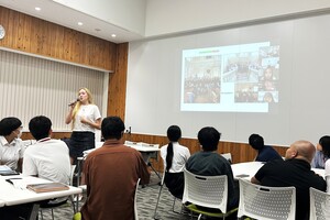 カミラさんがメンバーの前で話している写真