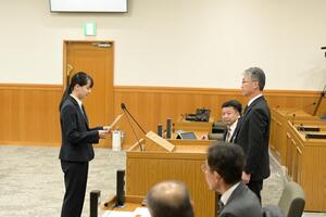 若者議会議長が市長の前で答申書を読み上げている写真