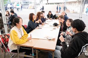 新城市の若者や海外ニューキャッスルの若者がテーブルを囲んで笑顔で話している写真